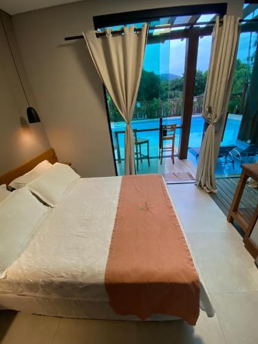 a bedroom with a bed and a view of a pool at El Shadday Pousada Boutique in Ubatuba