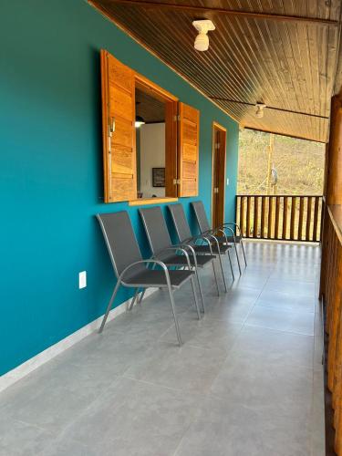 a row of chairs in a room with a blue wall at Rancho do Léo in Conceição do Mato Dentro