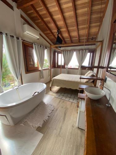 a bathroom with a bath tub and a bed at El Shadday Pousada Boutique in Ubatuba