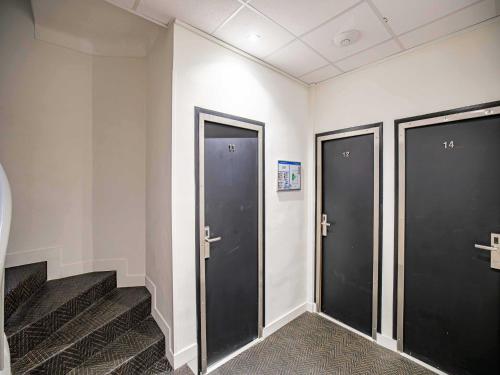 Une rangée de trois ascenseurs dans une pièce avec des escaliers dans l'établissement Résidence AVATON Cannes Centre, à Cannes