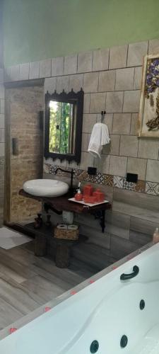 a bathroom with a tub and a table and a mirror at chale opucv in Gonçalves