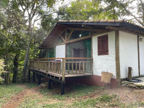 a small white house with a wooden porch at chale opucv in Gonçalves
