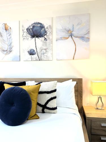 a bedroom with four paintings on the wall above a bed at 38 Suburban Retreat 3br 2ba Babyfriendly in Hocking