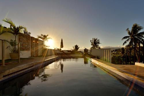 a pool of water with palm trees and the sunset at Ogma Suites Legazpi in Legazpi