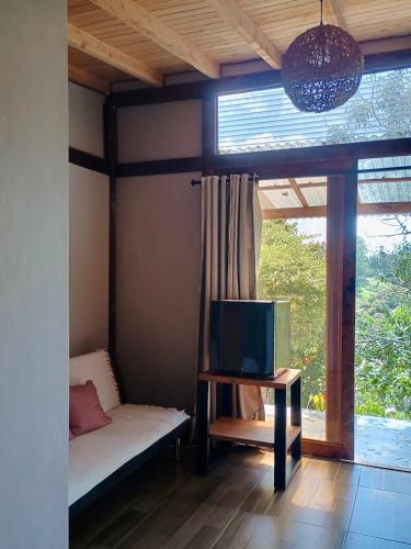 a room with a couch and a tv and a window at Quirama Lodge in Carmen de Viboral