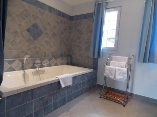 a bathroom with a tub and a window at Au Relais Provencal in Bagnols-en-Forêt