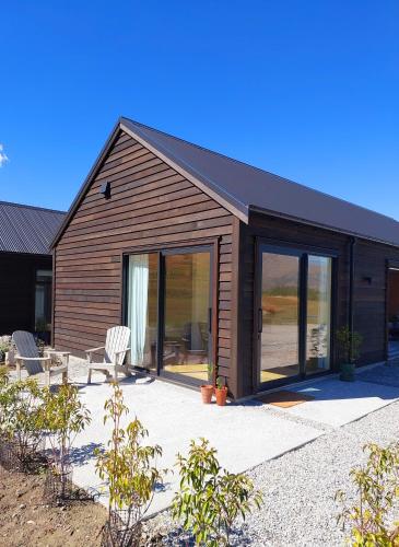a house with glass doors and two white chairs at Station Rise Retreat in Queenstown