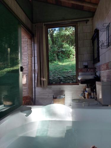 a bath tub in a bathroom with a window at chale opucv in Gonçalves