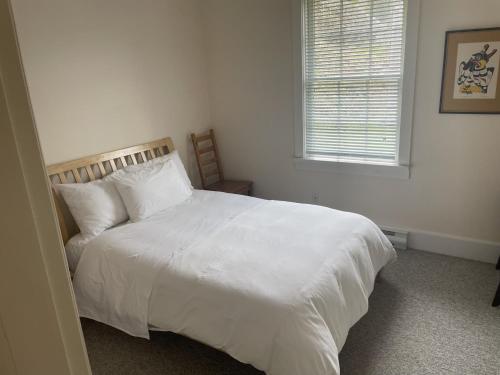 a bedroom with a white bed and a window at Seine Boat Inn in Alert Bay