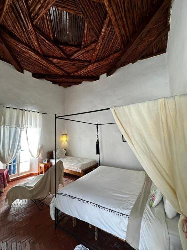 a bedroom with two beds and a wooden ceiling at Behind js in Essaouira
