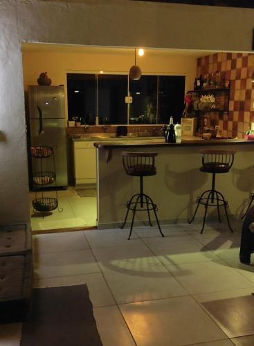 a kitchen with a counter and two bar stools at Sitio Vagalumes em Engenheiro Passos RJ próximo a Penedo in Resende