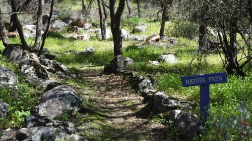 a trail with a blue sign next to some rocks at Little Valley Inn in Mariposa