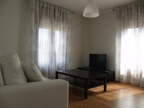 sala de estar con sofá blanco y mesa en Apartamentos Las Casitas de El Blasón, en Coca