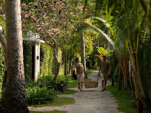 two people walking down a path in a garden at Kayumanis Jimbaran Private Villas & Spa in Jimbaran