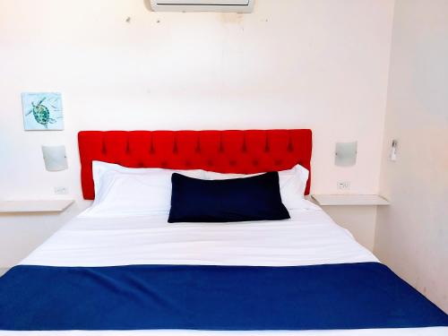 a red and white bed with a blue pillow on it at Departamento 21, cama king, cocineta , cerca del CAS,CIMA, CRIT, centro de gobierno y galerias mall in Hermosillo