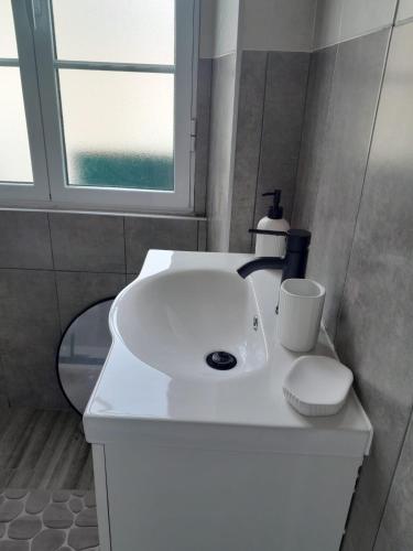 a white sink in a bathroom with a window at Cozy Nest in Bretanha