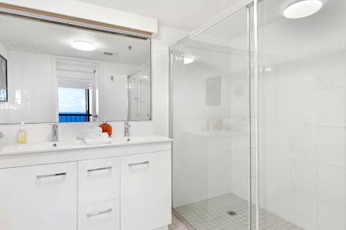 Un baño blanco con ducha y lavabo. en Beach retreat with balcony and views, en Gold Coast