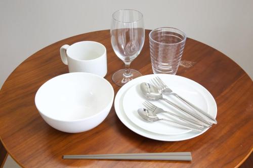 a wooden table with white plates and silverware on it at Isole le Olena 201 in Naha