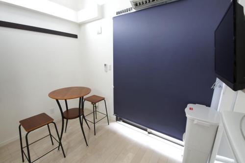 a room with a table and two chairs and a large screen at Isole le Olena 201 in Naha