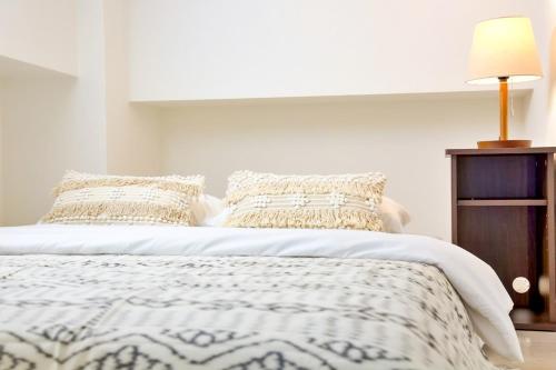 a white bed with a white comforter and pillows at Isole le Olena 201 in Naha