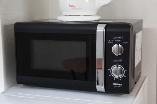 a black microwave with a cup on top of it at Isole le Olena 201 in Naha