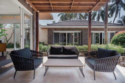 a patio with two chairs and a couch at Coconut Grove Villa by Betterplace in Ubud