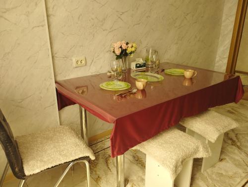 a table with plates and a vase of flowers on it at Уютный уголок Фрунзе in Bishkek