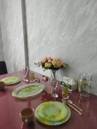 a table with plates and glasses and a vase with flowers at Уютный уголок Фрунзе in Bishkek