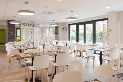 une salle à manger avec des tables et des chaises blanches dans l'établissement Kyriad Saint-Etienne Centre, à Saint-Étienne