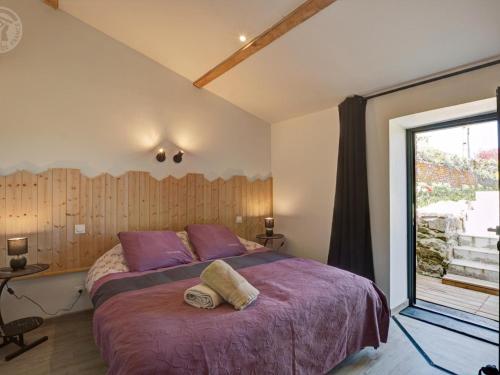 una camera da letto con un letto con lenzuola viola e una finestra di Gîte de charme 18ème avec spa et terrasse, St-Julien-Molin-Molette - FR-1-496-335 a Saint-Julien-Molin-Molette