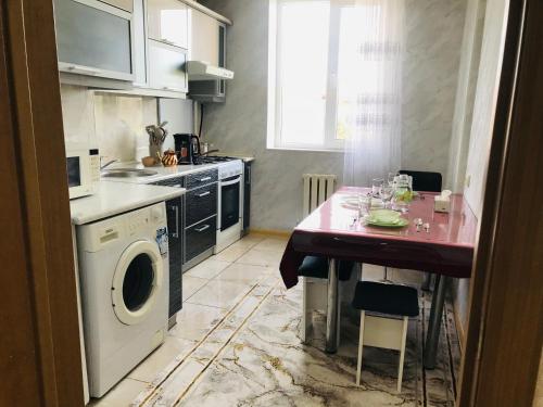 a kitchen with a table and a washing machine at Уютный уголок Фрунзе in Bishkek