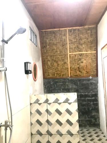 a bathroom with a shower with a checkered floor at Bello Bungalow in Batukliang