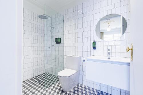 a white tiled bathroom with a toilet and a sink at The Lakes Hotel, Rosebery in Sydney