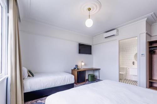 a bedroom with two beds and a bathroom at The Lakes Hotel, Rosebery in Sydney
