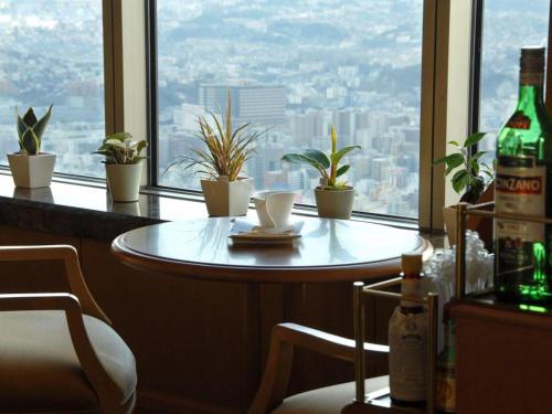 a table and chairs in front of a window with plants at Yokohama Royal Park Hotel in Yokohama