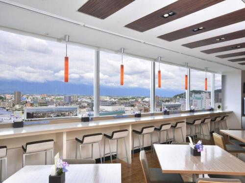 a restaurant with tables and chairs and large windows at Premier Hotel Cabin Matsumoto in Matsumoto