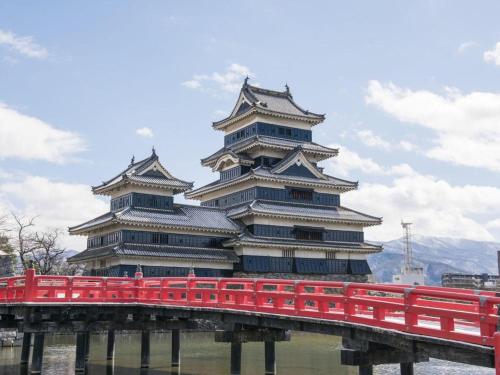 a large building with a red bridge in front of it at Premier Hotel Cabin Matsumoto in Matsumoto