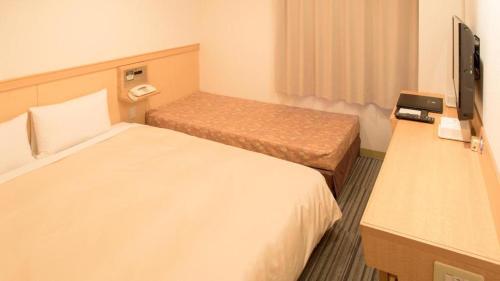 a hotel room with two beds and a flat screen tv at Premier Hotel Cabin Matsumoto in Matsumoto