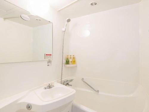 a white bathroom with a sink and a mirror at Premier Hotel Cabin Matsumoto in Matsumoto