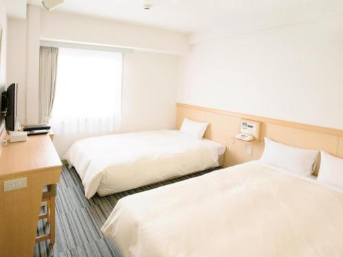 a hotel room with two beds and a desk at Premier Hotel Cabin Matsumoto in Matsumoto