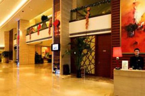 a man sitting at a counter in a lobby at Ramada by Wyndham Zibo in Zibo