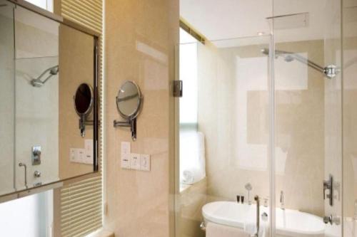 a bathroom with a shower and a toilet and a sink at Ramada by Wyndham Zibo in Zibo