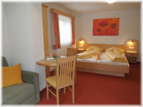 a bedroom with a bed and a table and a chair at Gästehaus Edelweiss in Sautens