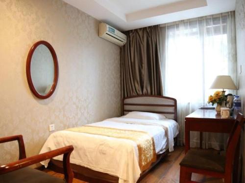 a bedroom with a bed and a desk and a mirror at GreenTree Inn Harbin Central Avenue in Harbin