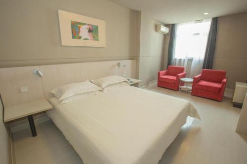 a bedroom with a white bed and two red chairs at Jinjiang Inn Luoyang Wangcheng Park Metro Station in Luoyang