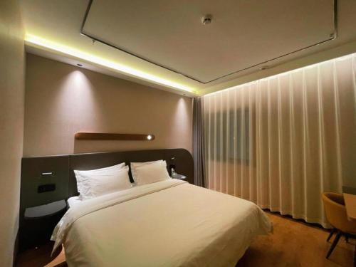 a bedroom with a large white bed and a window at GreenTree Inn Datong YundinGYAyuan Express Hotel in Datong