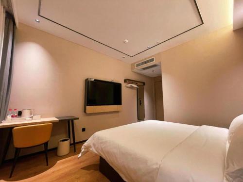 a hotel room with a bed and a desk and a tv at GreenTree Inn Datong YundinGYAyuan Express Hotel in Datong