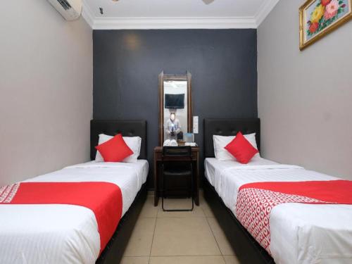 a room with two beds and a man in a mirror at OYO 1190 Nice Stay hotel in Raub