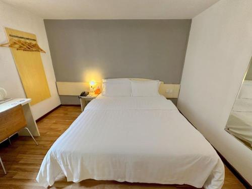 a bedroom with a large white bed and a desk at 7 Days Inn Guangzhou Zoo Huanghuagang Metro Station in Guangzhou