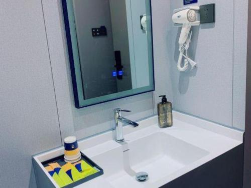 a bathroom sink with a mirror and a phone at 7 Days Inn Guangzhou Zoo Huanghuagang Metro Station in Guangzhou